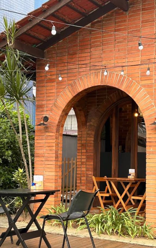 Varanda com arcos de tijolos, plantas e mesas